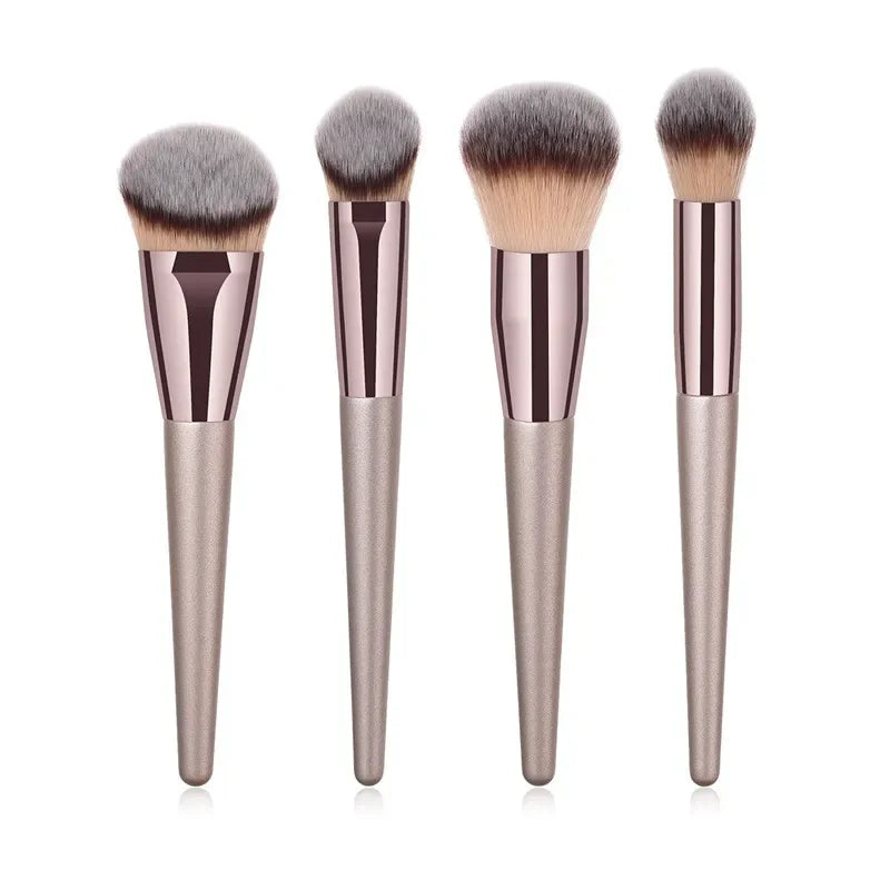 Champagne luxury makeup brush set with four soft, metallic-handle brushes on white background.