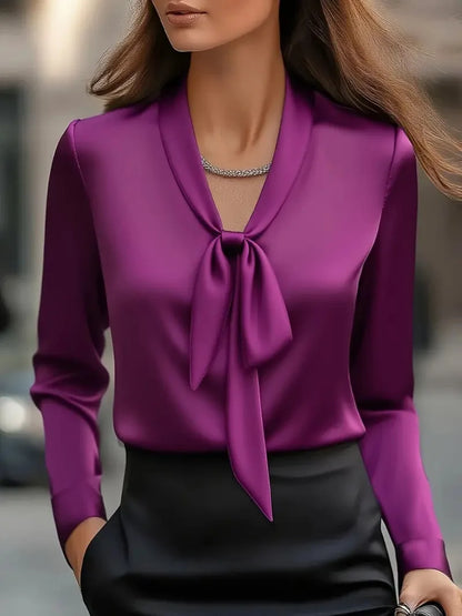 Elegant woman wearing a purple satin bow blouse paired with a black skirt, showcasing luxury fashion style