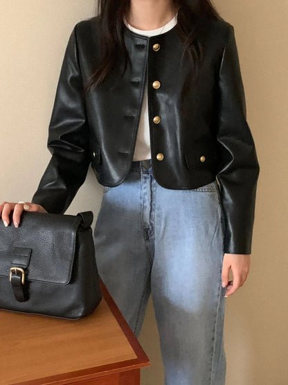 Front view of black vintage leather jacket with gold buttons worn with light blue jeans, next to black leather bag