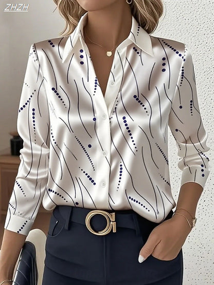 Woman wearing a white geometric striped satin blouse with black and blue lines, paired with navy pants and a gold belt