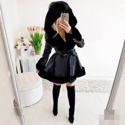 Woman wearing black hooded faux fur parka with belt and thigh-high boots in modern white room