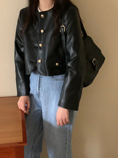 Woman wearing black vintage leather jacket with gold buttons and carrying black leather bag