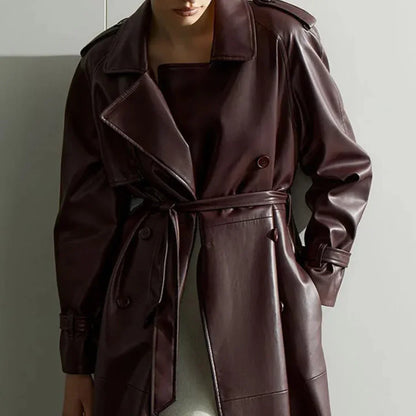 Woman wearing long dark brown faux leather trench coat with belt and button details