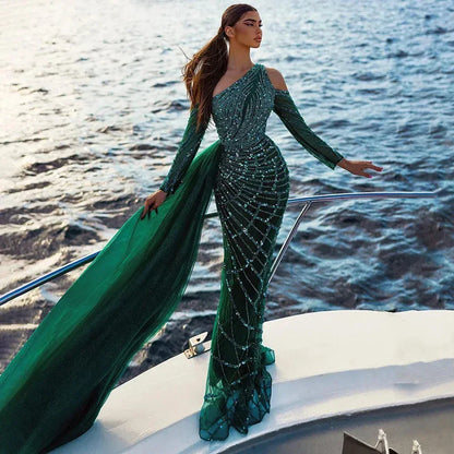 Woman in a luxury dark green beaded mermaid gown posing on a yacht by the ocean