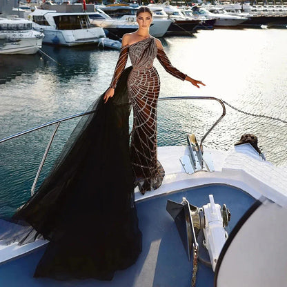 Elegant woman in a luxury beaded black mermaid gown with long train posing on a yacht deck