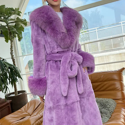 Woman wearing luxury purple faux fur trench coat with large collar and cuffs indoors by window