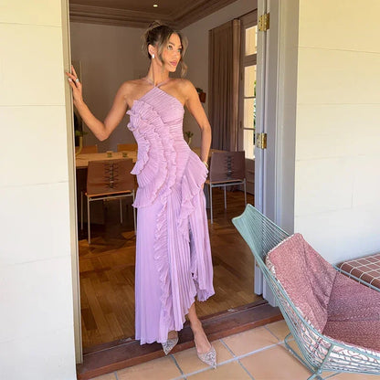 Woman in luxury lilac chiffon maxi dress with ruffle details standing at doorway in stylish home interior