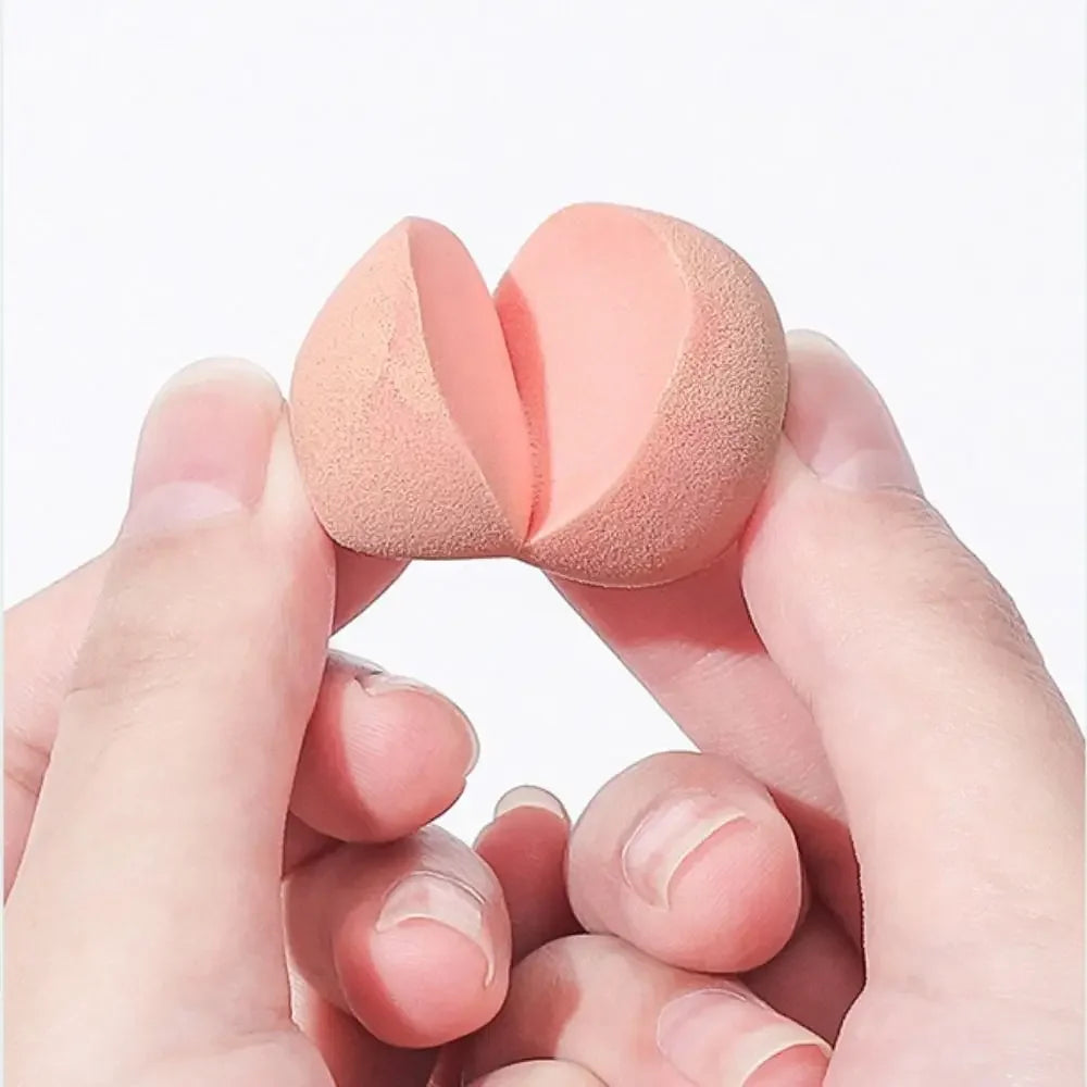 Peach-shaped luxury makeup sponge held between fingers against a light background