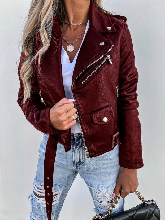 Woman in maroon slim fit PU leather jacket and ripped jeans holding black chain handbag