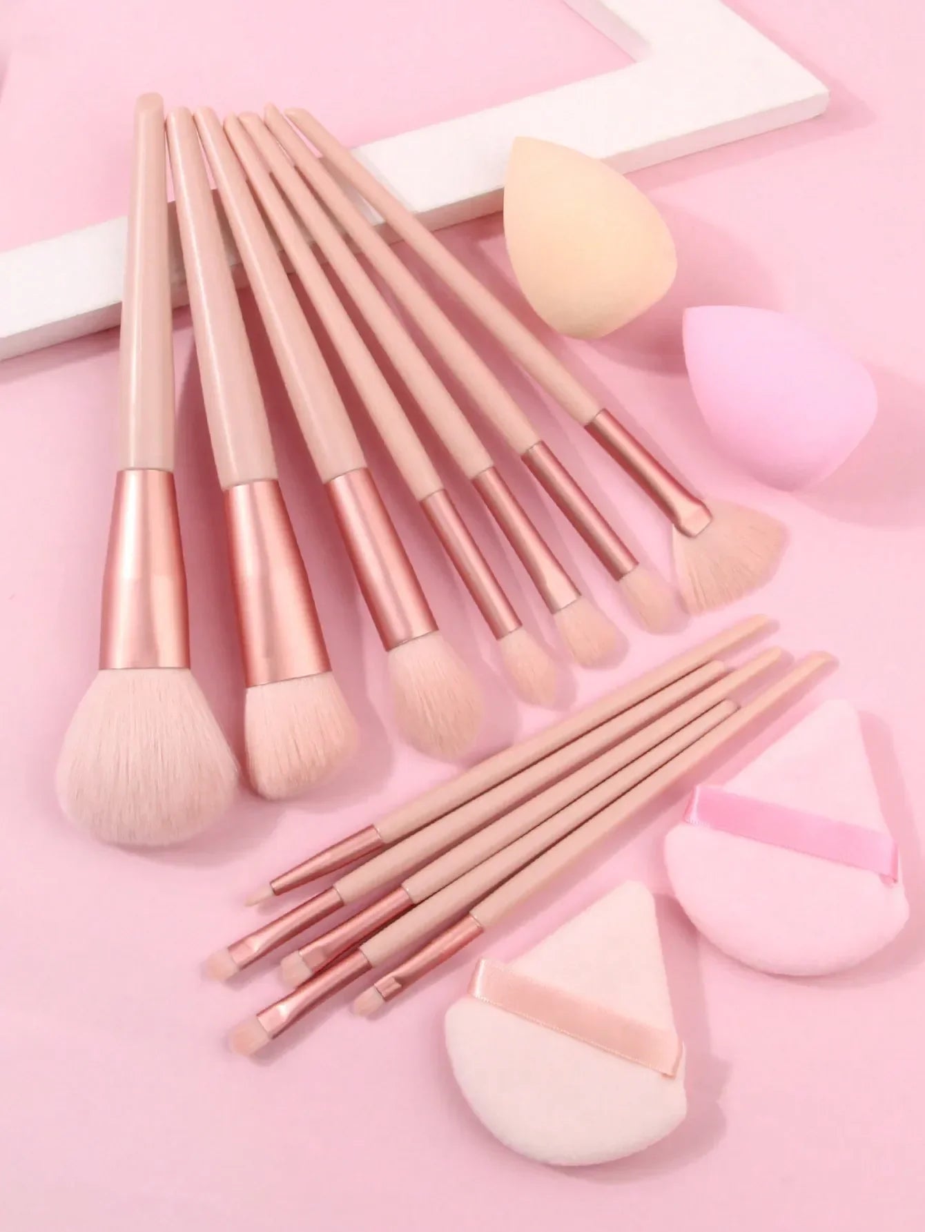 Luxury soft makeup brush set of 12 with beauty sponges on a pink background