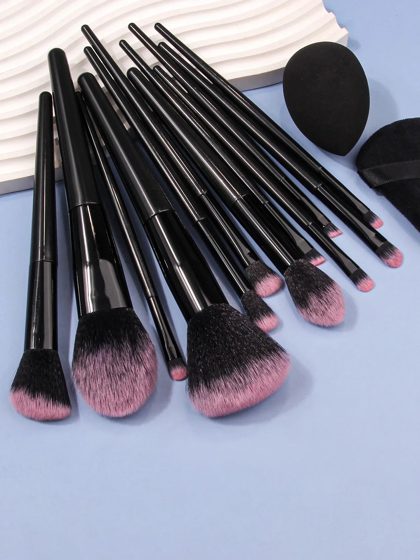 Luxury soft makeup brush set with black handles and pink bristles on a blue background