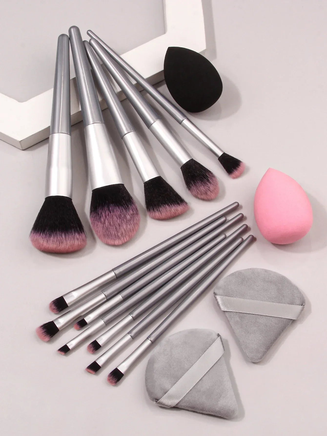 Luxury makeup brush set with silver handles, pink bristles, two sponges, and two powder puffs
