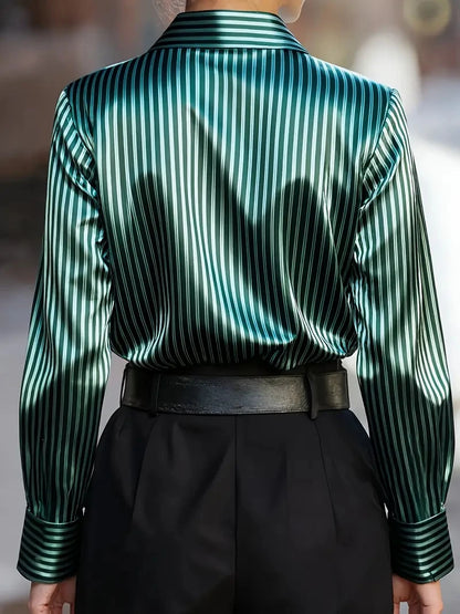 Back view of a woman wearing a green satin striped silk blouse paired with black high-waisted pants and a leather belt