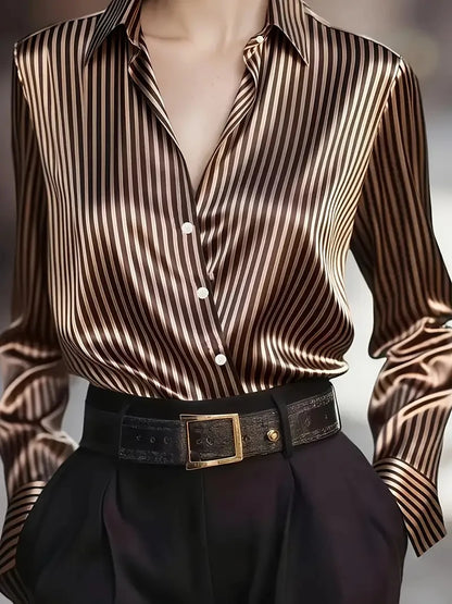 Woman wearing a satin striped silk blouse tucked into black high-waisted pants with a black leather belt