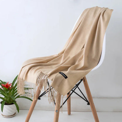 Beige cashmere scarf with fringes on white modern chair, indoor minimal decor