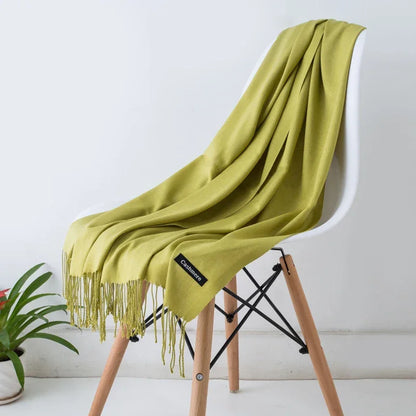 Light green cashmere scarf with fringe draped over modern white chair, indoor setting