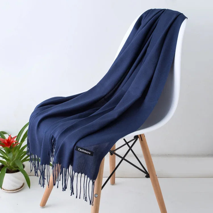 Navy blue women's cashmere scarf draped over white chair with wooden legs, autumn winter wrap