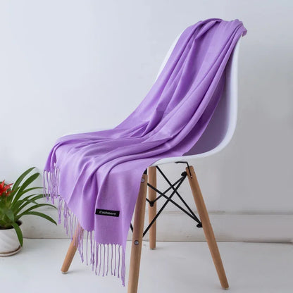 Soft lilac cashmere scarf draped over modern white chair with wooden legs in minimalist setting