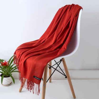 Solid red women's cashmere scarf draped over white modern chair with wooden legs, autumn winter warm shawl