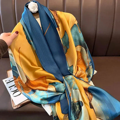 Colorful silk scarf with blue, yellow, and gold floral pattern draped on a brown bench