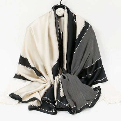 Elegant black, gray, and cream silk scarf with geometric diamond border pattern on hanger