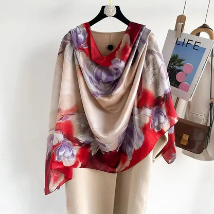 Silk floral scarf with purple and red flowers draped over beige coat on hanger