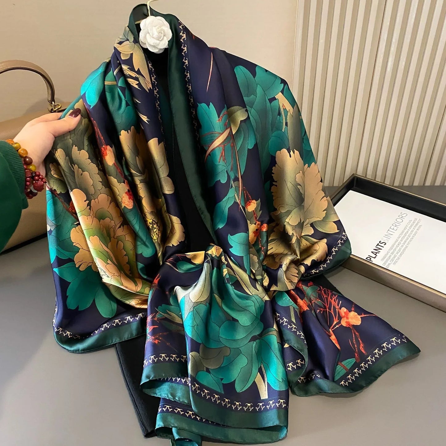 Silk floral scarf with green and gold leaf print draped on table
