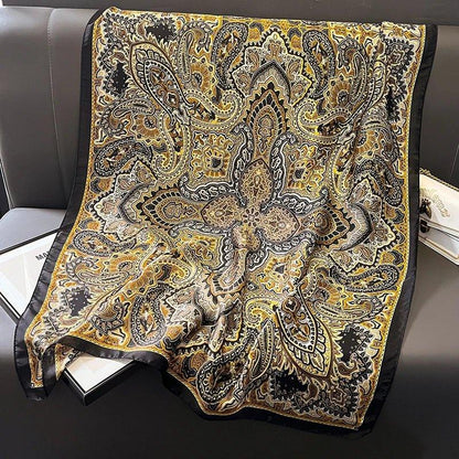 Yellow and black paisley silk scarf with intricate pattern draped on a gray sofa