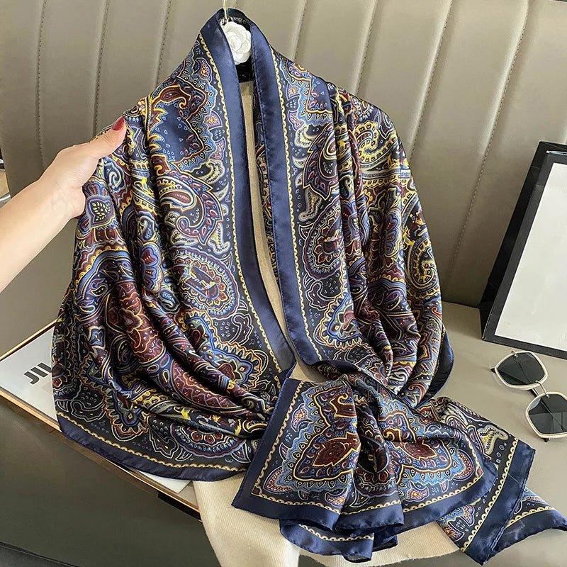Silk paisley scarf with blue, gold, and burgundy pattern draped on a beige seat