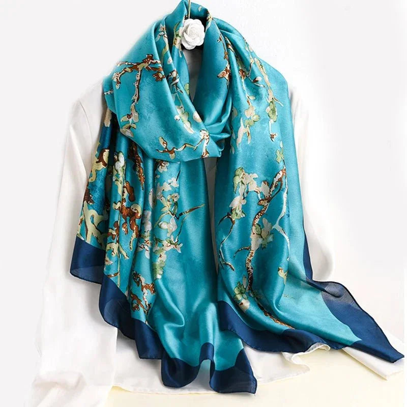 Blue silk scarf with floral branch print draped over white shirt on hanger
