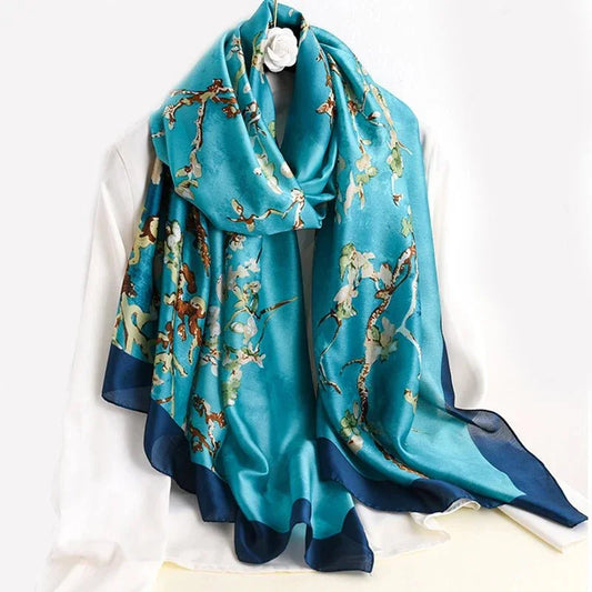 Blue silk scarf with floral print draped on a white blouse, elegant fashion accessory