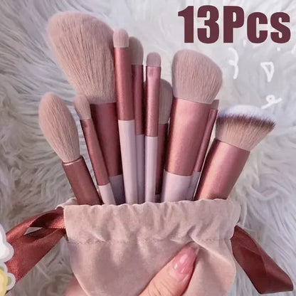 Luxury 13-piece makeup brush set with pink handles in a velvet pouch on a soft surface