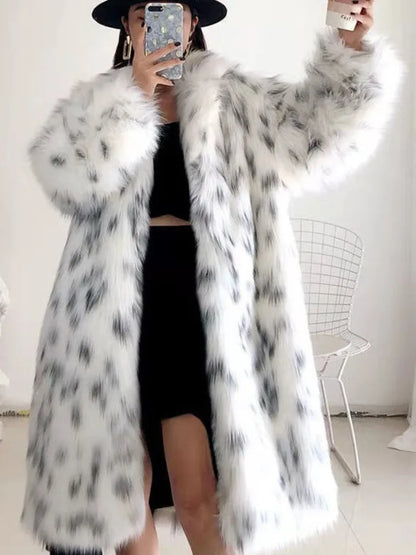 Woman wearing long white faux fur winter coat with black spots, black dress, and hat indoors